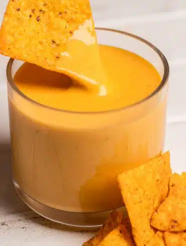 corn chip dipping into a nacho cheese sauce with hidden vegetables