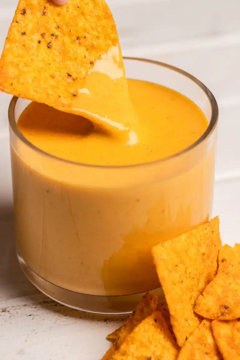 corn chip dipping into a nacho cheese sauce with hidden vegetables